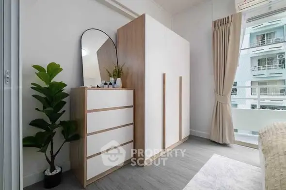 Modern bedroom with sleek wardrobe and dresser, large window with city view, and stylish decor.