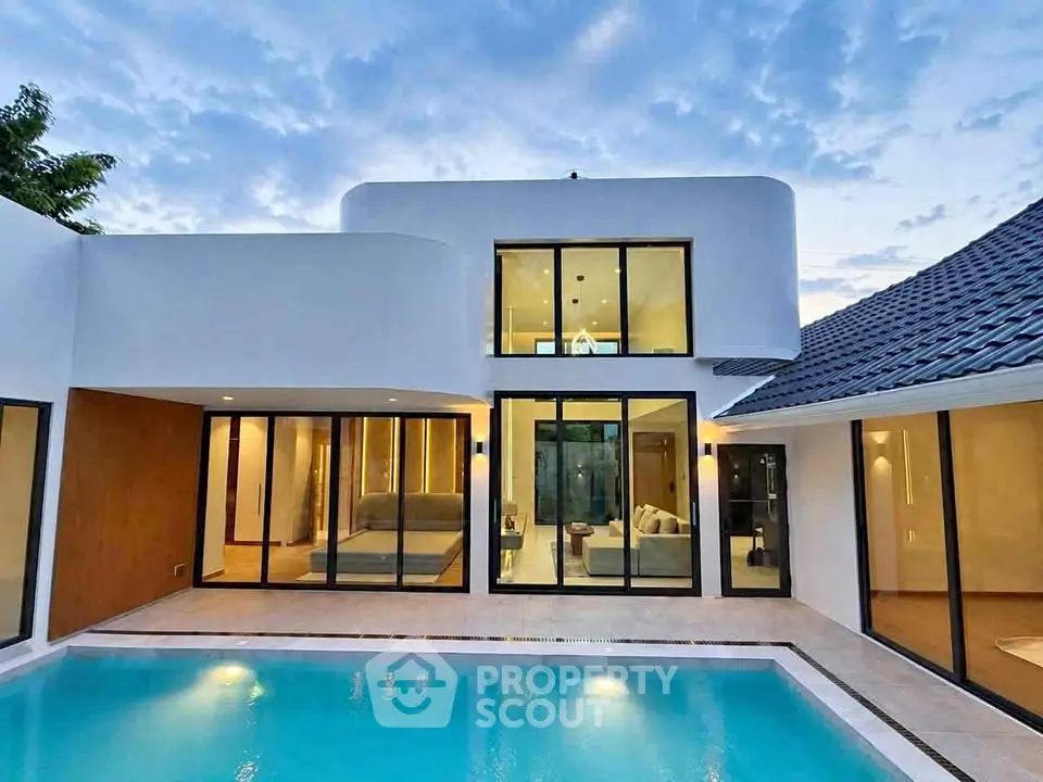 Modern luxury home with pool and large windows at sunset