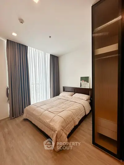 Modern bedroom with large window and stylish decor in a contemporary apartment.