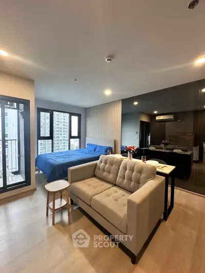 Modern studio apartment with cozy living area and city view balcony.