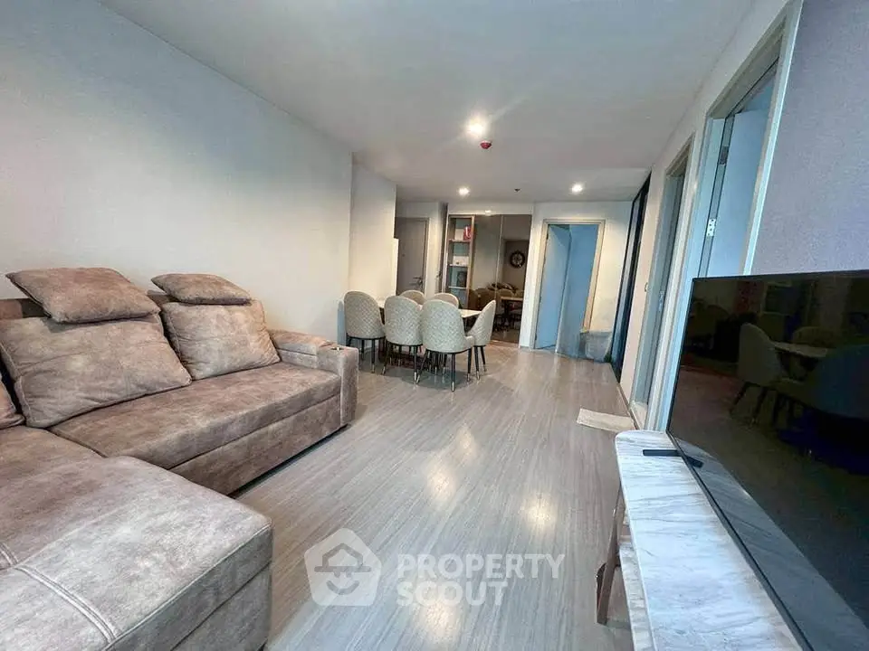 Spacious modern living room with plush sofa and dining area in open layout apartment.