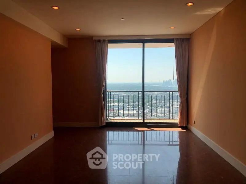 Spacious living room with large window offering stunning city view and ample natural light.