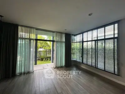 Spacious living room with large windows and garden view, perfect for natural light lovers.