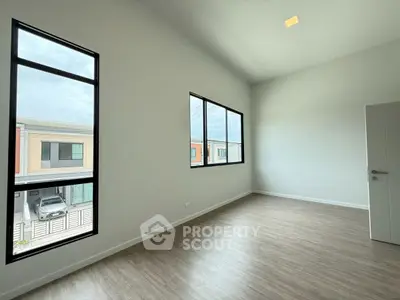 Spacious empty room with large windows and modern flooring in a contemporary home.