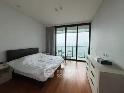 Spacious bedroom with stunning city view and balcony access, featuring modern furniture and hardwood floors.