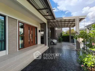 Modern home entrance with covered carport and lush garden, perfect for stylish living.