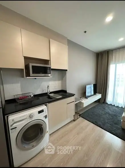 Modern studio apartment with compact kitchen and washing machine