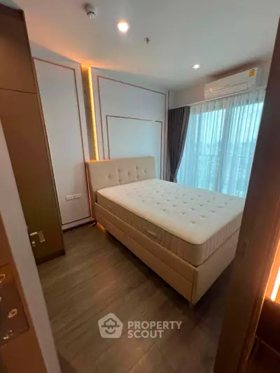 Modern bedroom with stylish decor and large window offering natural light.