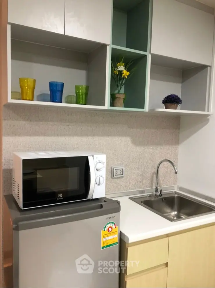 Modern compact kitchen with microwave, fridge, and stylish shelving