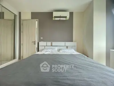 Modern bedroom with sleek design and air conditioning unit, featuring a comfortable bed and mirrored wardrobe.