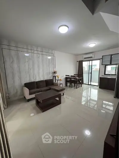 Spacious modern living room with elegant decor and dining area, featuring large windows and sleek furniture.