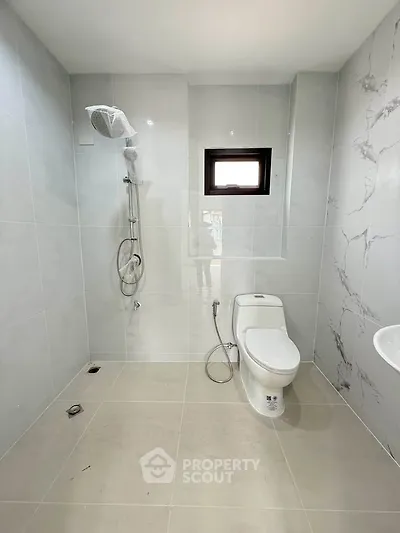 Modern bathroom with sleek shower and toilet in minimalist design.