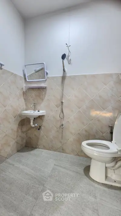Modern bathroom with tiled walls and floor, featuring a shower and toilet.