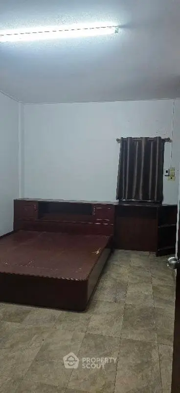 Spacious bedroom with wooden furniture and tiled flooring, ideal for comfortable living.