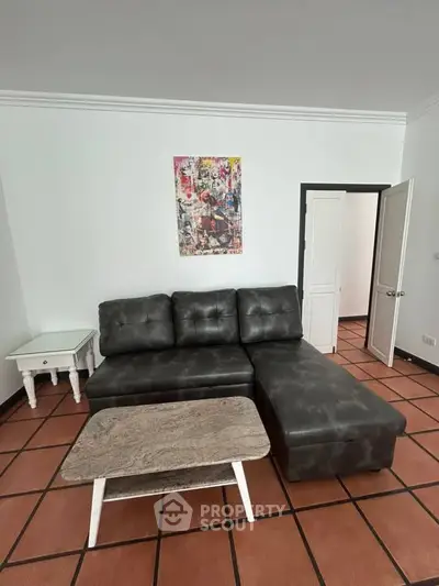 Chic living room with modern black leather sofa and stylish coffee table on terracotta tiles.