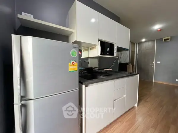 Modern kitchen with sleek cabinetry and stainless steel fridge in stylish apartment.
