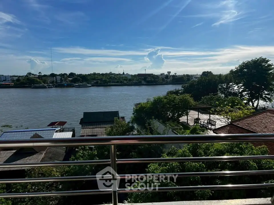 Stunning river view from a balcony with lush greenery and clear blue skies.