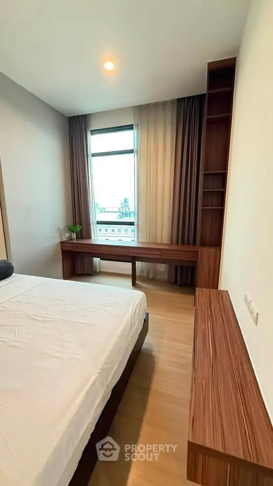 Modern bedroom with wooden furniture and large window offering city view