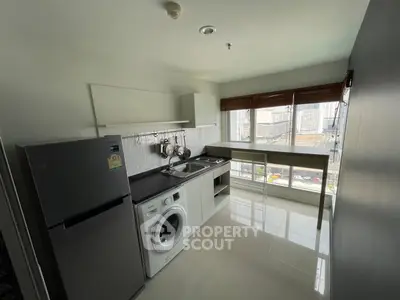Modern kitchen with city view, featuring washing machine and fridge in sleek design.