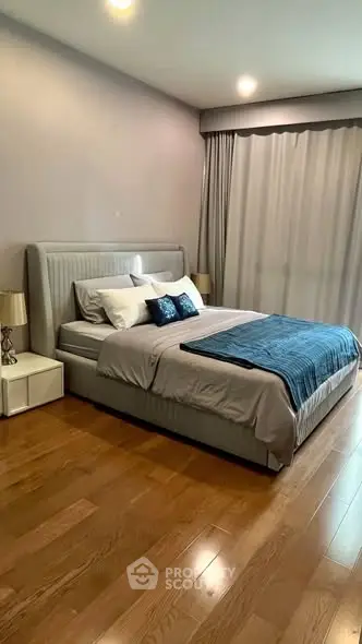 Elegant bedroom with modern decor and hardwood flooring, featuring a plush bed and ambient lighting.