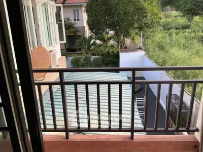 Charming balcony view overlooking lush greenery and neighboring homes, perfect for relaxation.