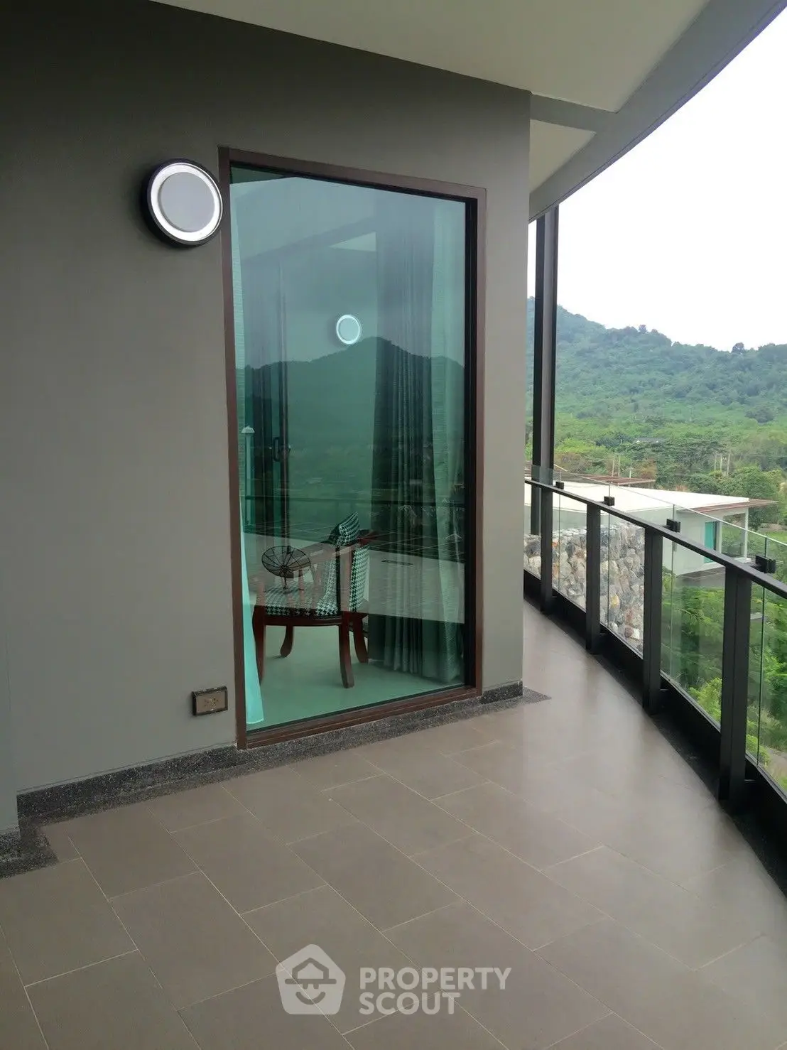 Spacious balcony with panoramic hillside views, featuring sleek floor tiles and a modern glass barrier, perfect for outdoor relaxation and entertaining.
