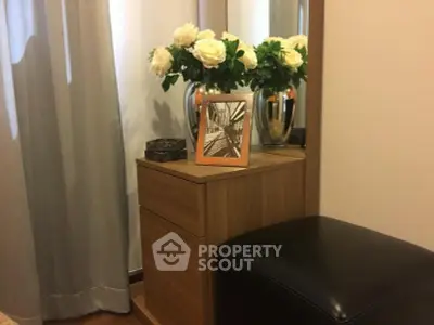 Elegant bedroom corner with wooden dresser, floral decor, and modern photo frame.