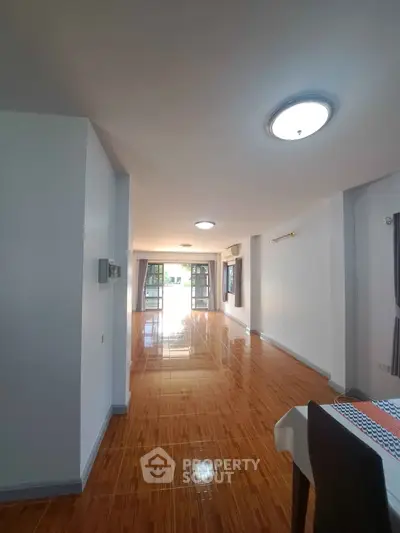 Spacious and bright living room with polished wooden floors and large windows.