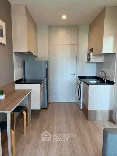 Modern compact kitchen with sleek appliances and wooden flooring