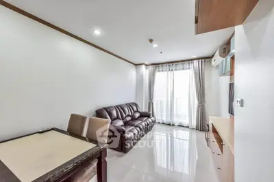 Spacious living room with leather sofa and modern decor, featuring large windows for natural light.
