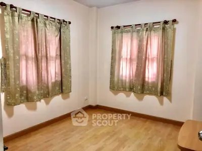 Cozy bedroom with wooden flooring and soft pink curtains