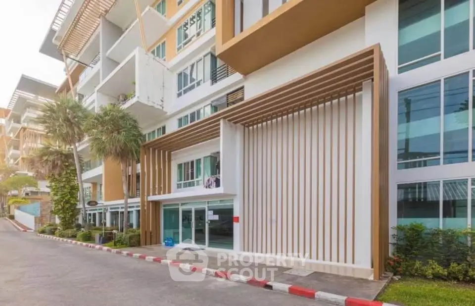 Modern apartment building exterior with sleek design and palm trees, showcasing urban living.