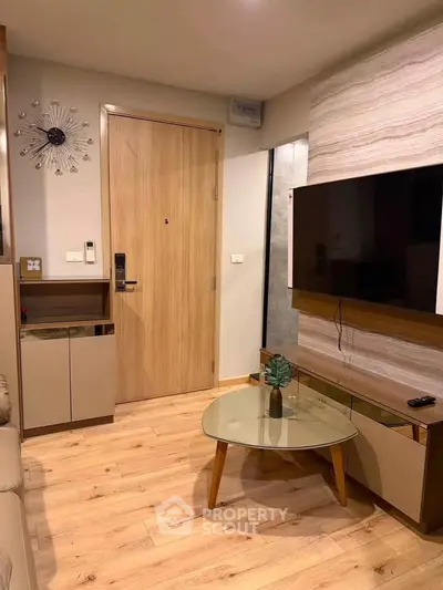 Modern living room with stylish decor and wooden flooring, featuring a wall-mounted TV and sleek furniture.