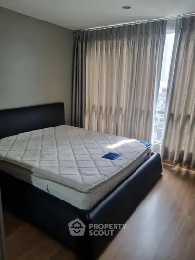 Cozy bedroom with large window and modern bed frame, perfect for relaxation.