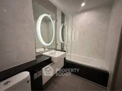 Modern bathroom with elegant fixtures and illuminated mirror in luxury apartment.