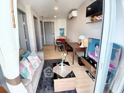Modern living room with stylish decor and natural light, featuring a cozy sofa and entertainment area.