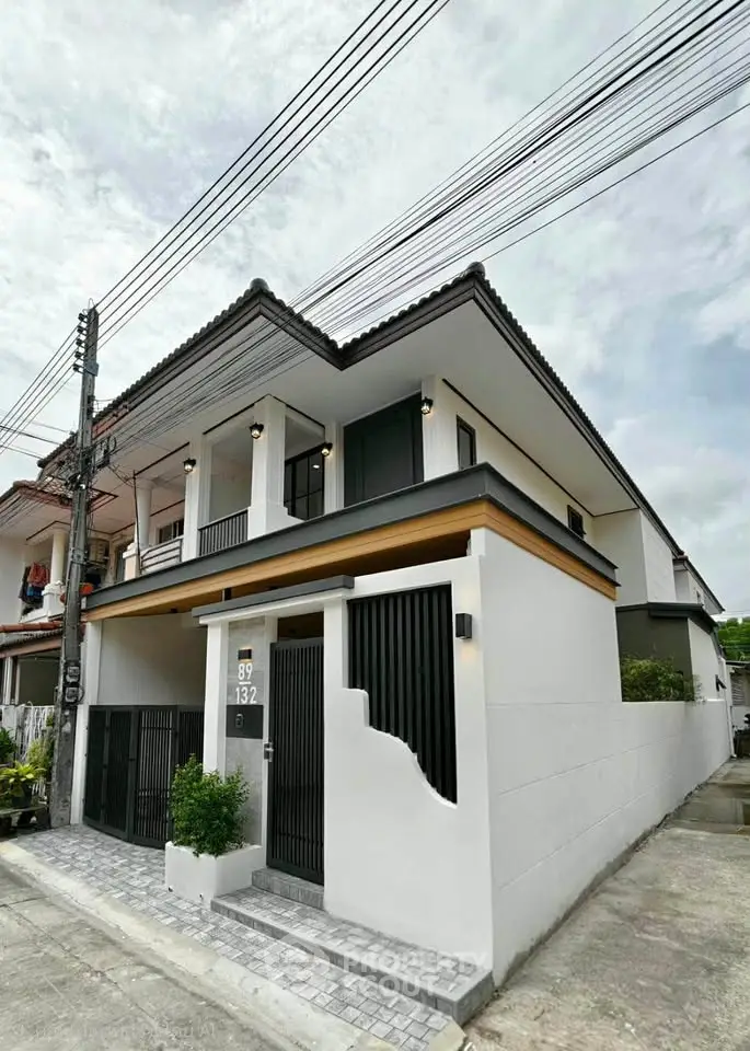 Modern two-story house with sleek design and gated entrance in a suburban neighborhood.