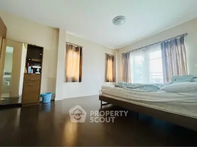 Spacious bedroom with large windows and wooden flooring, offering ample natural light and a cozy atmosphere.