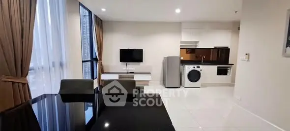 Modern open-plan living room with kitchen, featuring sleek appliances and elegant dining area.