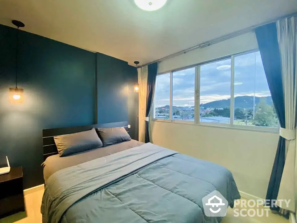 Cozy bedroom with large window offering scenic mountain view, modern decor and ambient lighting.