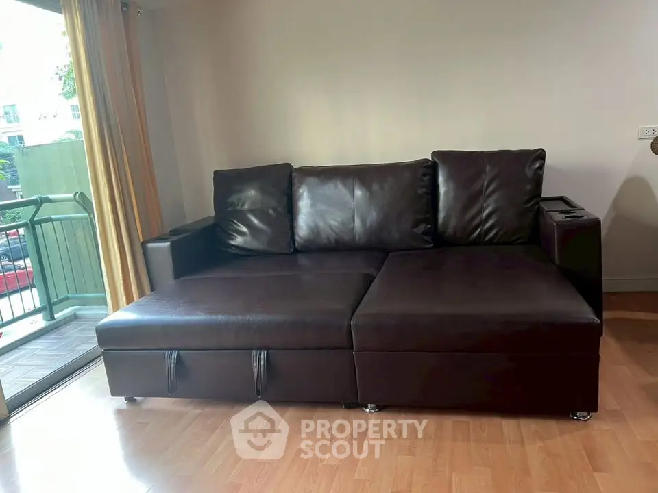 Spacious living room with modern leather sofa and balcony access