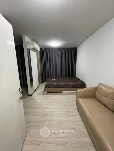 Modern bedroom with minimalist design, featuring a cozy bed and stylish sofa.