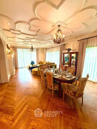 Luxurious living room with elegant dining area, ornate ceiling, and hardwood floors in a spacious open layout.