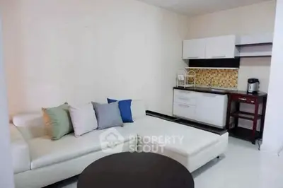 Modern living room with sleek white sofa and compact kitchen area.