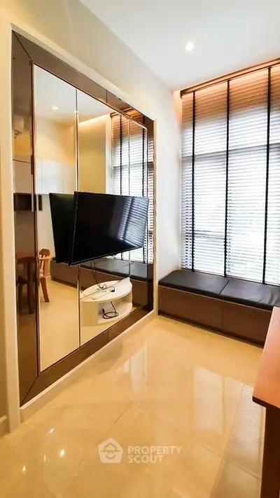 Modern living room with sleek TV setup and large windows for natural light.