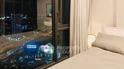 Luxurious bedroom with stunning city view at night, featuring cozy bedding and large window.