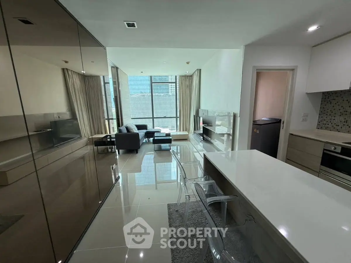 Modern open-layout living room with sleek kitchen and city view, featuring contemporary furniture and glossy finishes.