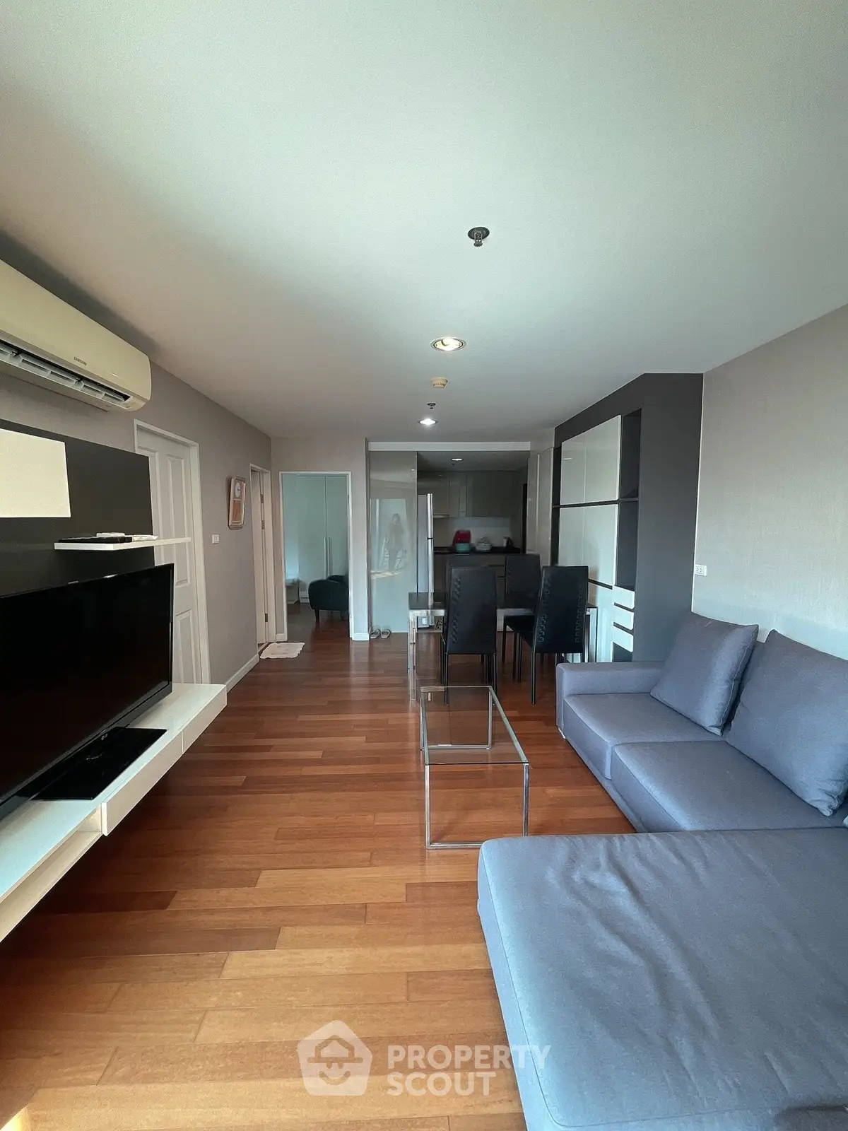 Spacious modern living room with sleek furniture and wooden flooring, perfect for comfortable living.