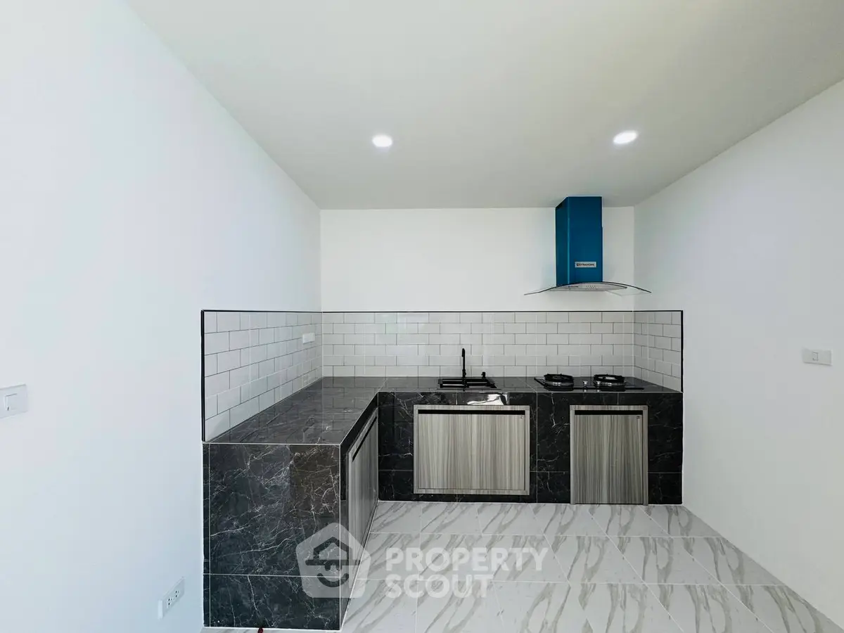 Modern minimalist kitchen with sleek black marble countertops and stainless steel appliances.