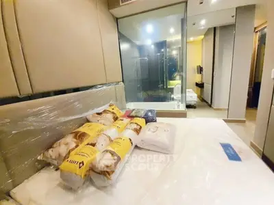 Modern bedroom with glass partition and cozy bedding in a stylish apartment.